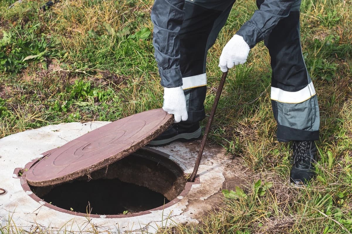 Technician opening a septic tank access lid for inspection
